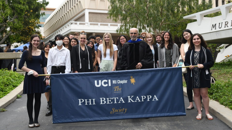 Students pose with the UCI Phi Beta Kappa banner at the 2023 induction ceremony.